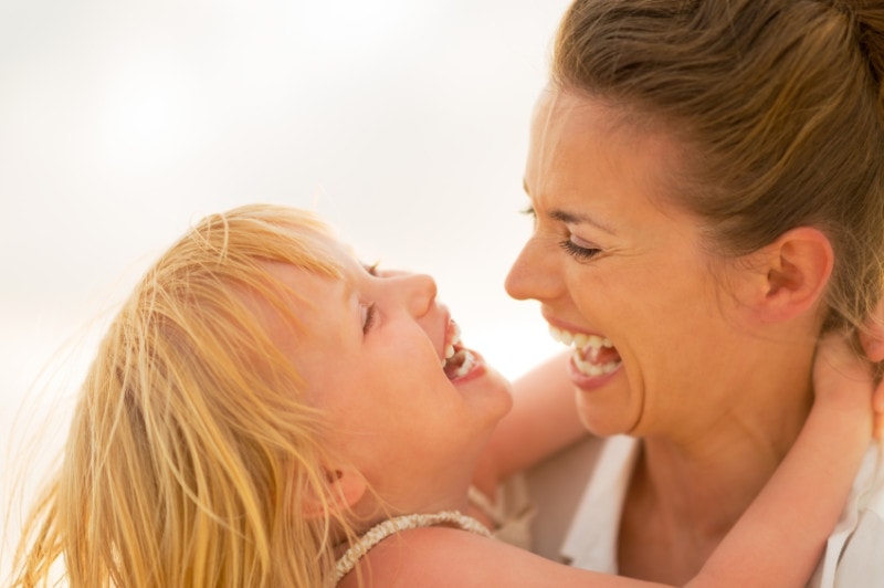 Portrait of smiling mother and baby girl hugging on the beach in the evening