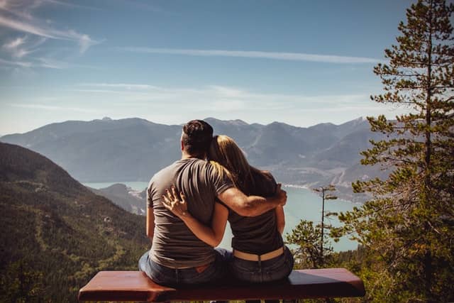 Un hombre y una mujer se abrazan viendo el horizonte